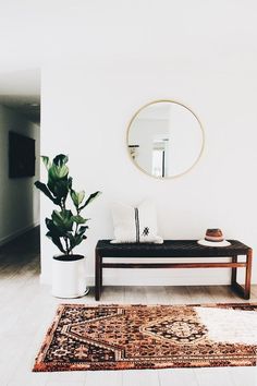 a living room with a couch, mirror and potted plant