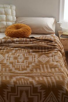 a bed with a brown blanket and pillows on top of it next to a window