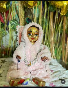 a small doll sitting on top of a bed next to some balloons and streamers