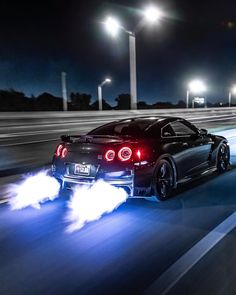 a black sports car driving down the road at night