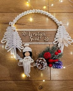 a christmas wreath with an angel and pine cones on the side, surrounded by lights