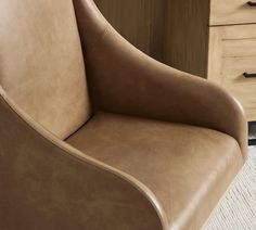 a brown leather chair sitting in front of a dresser