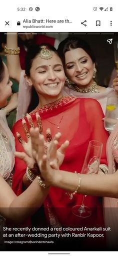 two women in red sari are hugging each other with their arms around one another