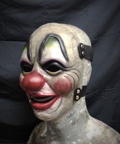 a creepy clown mask with red nose and green eyes