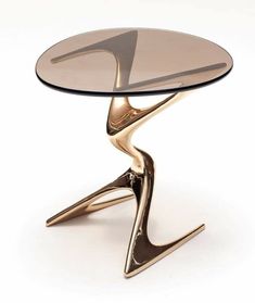 an artistically designed glass table with gold legs and a circular top, on a white background