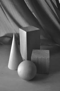 three wooden blocks and two balls on a tablecloth covered surface with drapes in the background