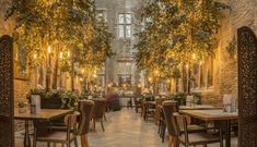 the interior of a restaurant with tables, chairs and plants growing on the brick walls