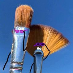 two brushes with funny faces on them are standing next to each other in front of a blue sky