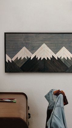 a painting hanging on the wall next to a suitcase and coat rack in a room