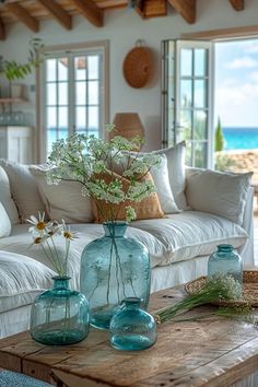 three vases with flowers are sitting on a coffee table in front of a couch