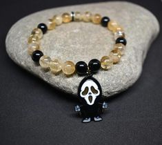 A killer combo for spooky season! Unleash your inner scream queen/king with this hauntingly beautiful Ghostface bracelet. Crafted with sleek Onyx beads and radiant Citrine accents, this piece is more than just an accessory - it's a statement. Whether you're a horror fan or simply looking for a unique piece to complete your Halloween look, this bracelet brings both edge and elegance.  Onyx is a strength-giving stone that offers support during difficult times, enhances personal power, and helps al Ghostface Bracelet, Citrine Bracelet, Emotional Strength, Crystal Therapy, Scream Queens, Hauntingly Beautiful, Les Chakras, Difficult Times, Personal Power