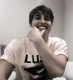 a young man smiles while sitting in front of a mirror