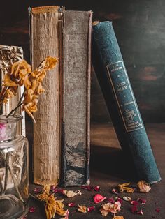 two books are next to each other with dried flowers in front of them on a table