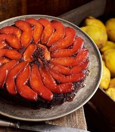 there is a chocolate cake with fruit on the plate next to lemons and potatoes