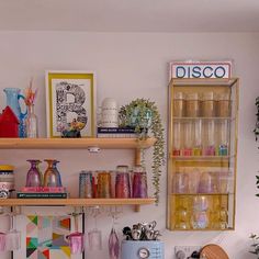 a kitchen filled with lots of counter top space and wooden shelves covered in glassware