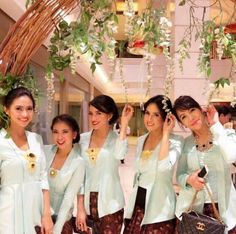 the women are all dressed up and posing together for a photo in front of some hanging plants