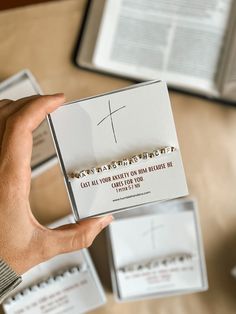 a person holding up a card with a cross on it in front of an open book