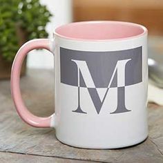 a pink and white coffee mug with the letter m on it