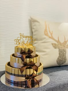 a three tiered cake sitting on top of a white plate next to a pillow