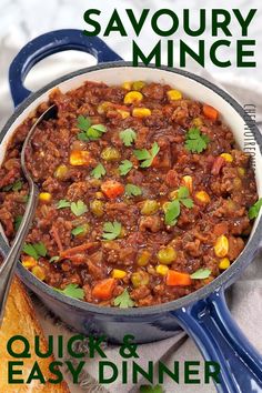 a blue pot filled with chili and corn next to a slice of bread on a plate