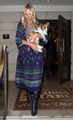 a woman holding a cat in her arms while walking out of a building with other people