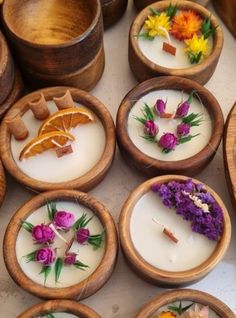 many small wooden bowls filled with different types of flowers and candles on top of a table