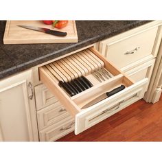 an open drawer in the middle of a kitchen counter with knives and utensils