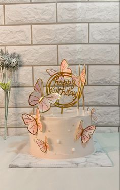 a white cake with pink butterflies on it and the words happy birthday written on top