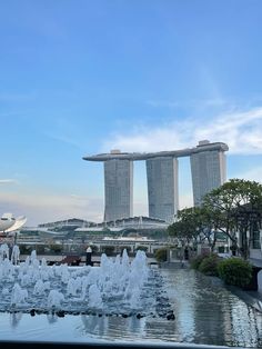 the water features in front of two tall buildings with fountains on each side and trees near by