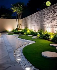 an outdoor garden at night with lights on the walls and green grass in the foreground