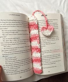 an open book with a pink and white crocheted bookmark