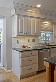 a kitchen with white cabinets and black counter tops