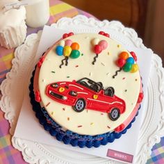 a birthday cake with balloons and a car on it