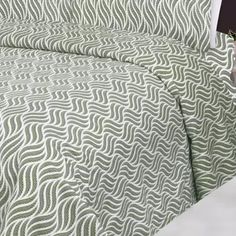 a bed covered in a green and white comforter