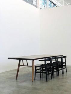 a table and four chairs are in an empty room with a white wall behind it