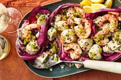 a plate full of shrimp and lettuce with lemon wedges