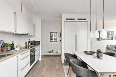 a kitchen and dining room with white walls, wood floors and an open floor plan