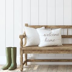 a wooden bench with two white pillows and green rubber boots on the floor next to it