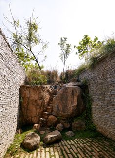 an outdoor area with rocks and grass on the ground next to a stone wall that has been built into it