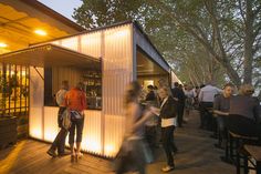 many people are standing outside at night on the deck with their food and drink carts