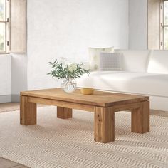 a living room with a couch, coffee table and rug on the floor in front of it