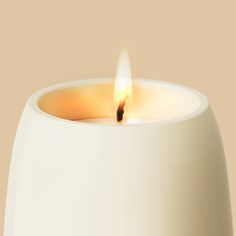 a lit candle is sitting in a white vase