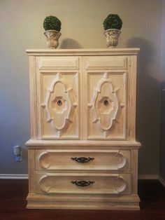 a white cabinet with two potted plants on top