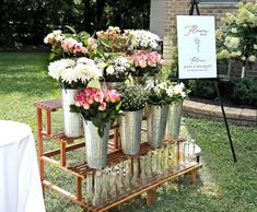 several vases filled with flowers sitting on a wooden stand in front of a sign