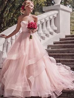 a woman in a pink dress standing on some stairs