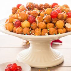 a white plate topped with fruit covered in sprinkles next to a bowl of strawberries