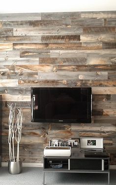 a living room with wood paneling on the wall and television mounted to the wall