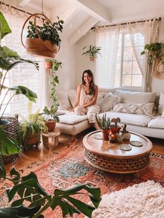 a woman sitting at a table in front of potted plants