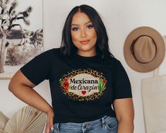 "Listing for the Spanish \"Mexicana de Corazon\" Latina T-shirt! Show your love for your mom, wife, friend, sister in your with this comfortable and casual t shirt that your Latina Mom, Sister or Friend would love to wear. This makes the best gift for them! * 100% combed and ring-spun cotton (heather colors contain polyester) * Fabric weight: 4.2 oz (142 g/m2) * Shoulder-to-shoulder taping * Side-seamed FIND MORE SPANISH TSHIRTS GO HERE: https://www.etsy.com/shop/SweetLizCo?ref=seller-platform-mcnav Care instructions: Machine wash cold and tumble dry low. *PLEASE verify your address before placing your order!  *RETURNS: Please check the size chart before placing an order. Instructions are there on how to choose size. I DO NOT OFFER EXCHANGE OR RETURNS when you order the wrong size. Only re Casual Short Sleeve Shirt For Cinco De Mayo, Mexican Shirts Woman, Latina T Shirt Ideas, Mexican Graphic Tees, Mexican Flag Shirt, Latina Af Shirt, Mexico Shirts, Mexican Shirts, Original Design