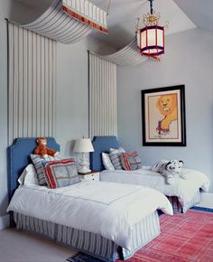 two beds in a room with lamps and pictures on the wall above them, one has a teddy bear